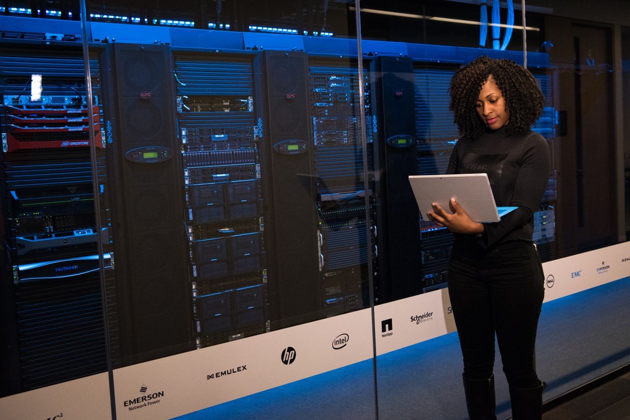 Mastering the First Impression: Your intriguing post title goes here A female engineer using a laptop while monitoring data servers in a modern server room.